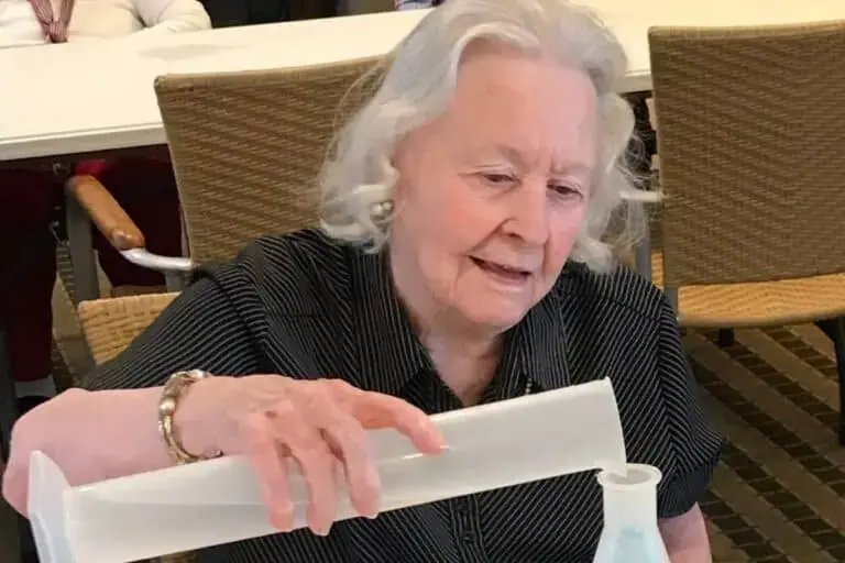 Senior woman with white hair engaged in a hands-on science activity, demonstrating that learning and discovery continue at any age